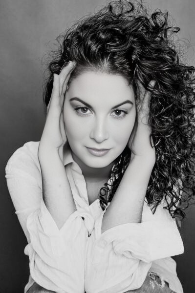 Entre Rizos — retrato expresivo en blanco y negro de una mujer con cabello rizado y manos junto al rostro